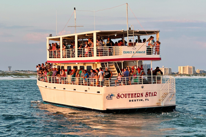 Crowded tour boat 'Southern Star' on water near Destin, FL, with sunset in the background.