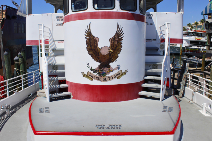 Boat deck with eagle mural and phrase 'Praise Be to God', flanked by two staircases.