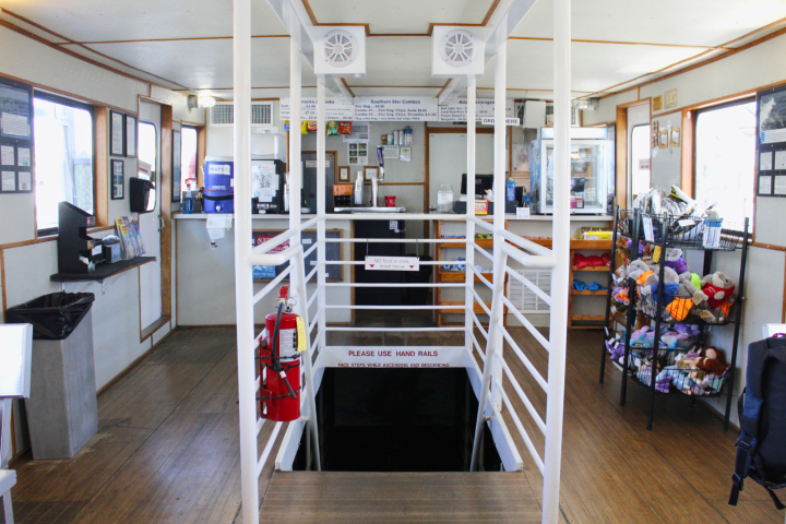 Interior of a ferry with stairway, life jackets, and snacks on display.