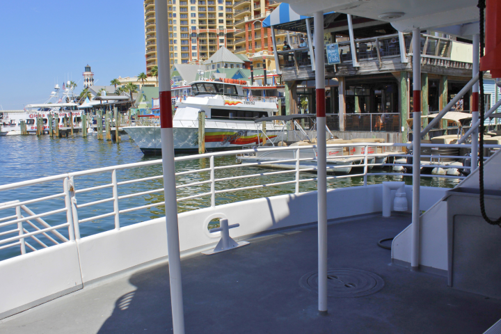 View of a marina from a boat deck, with buildings and boats in the background.