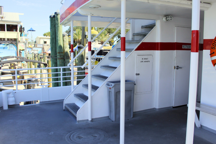 Ferry deck with stairs, restroom door, and 'life jackets' storage compartment.