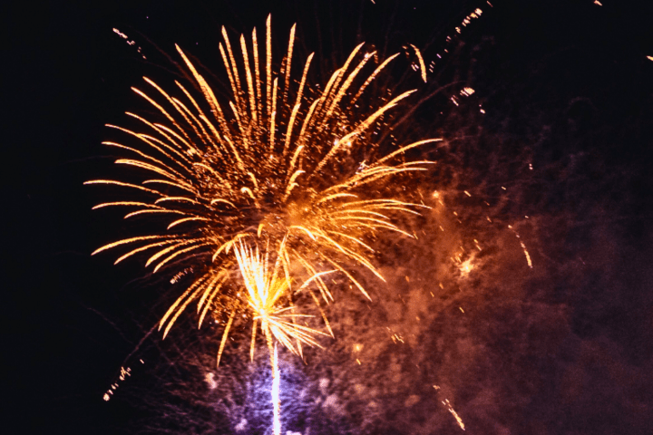 Bright orange fireworks burst against a dark night sky.